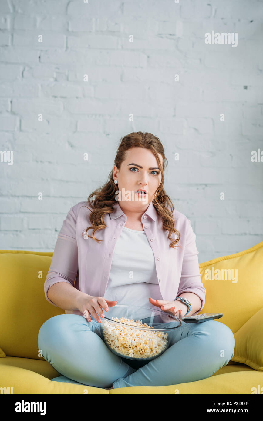 Surpris belle femme regarder film avec pop-corn à la maison Banque D'Images