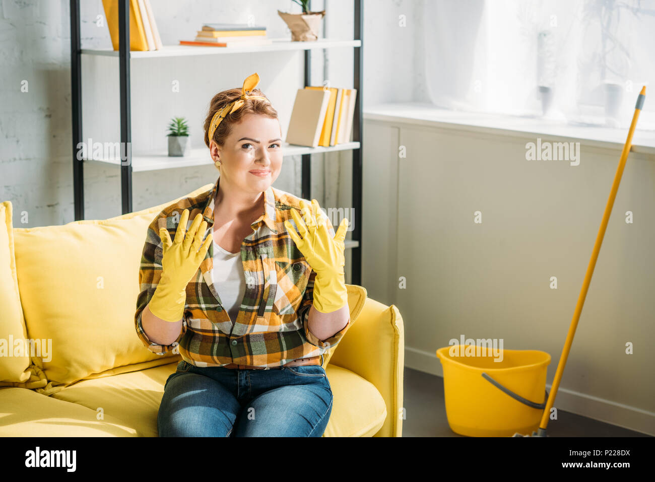 Jolie femme montrant les mains dans des gants en caoutchouc pour le nettoyage à la maison Banque D'Images