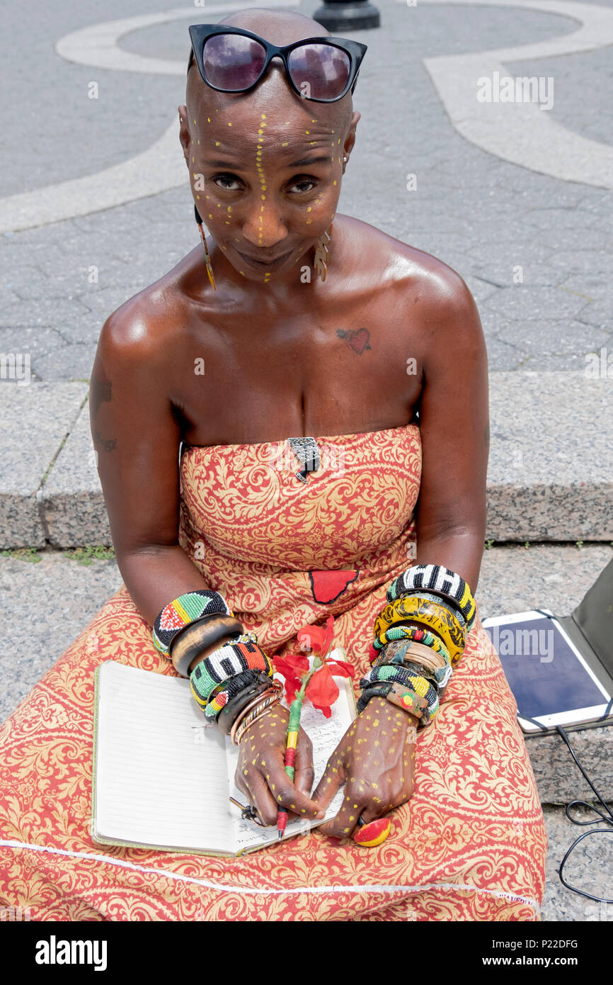 Une belle femme avec des points peint sur son visage et ses mains assis dans un parc à Manhattan, New York City. Banque D'Images