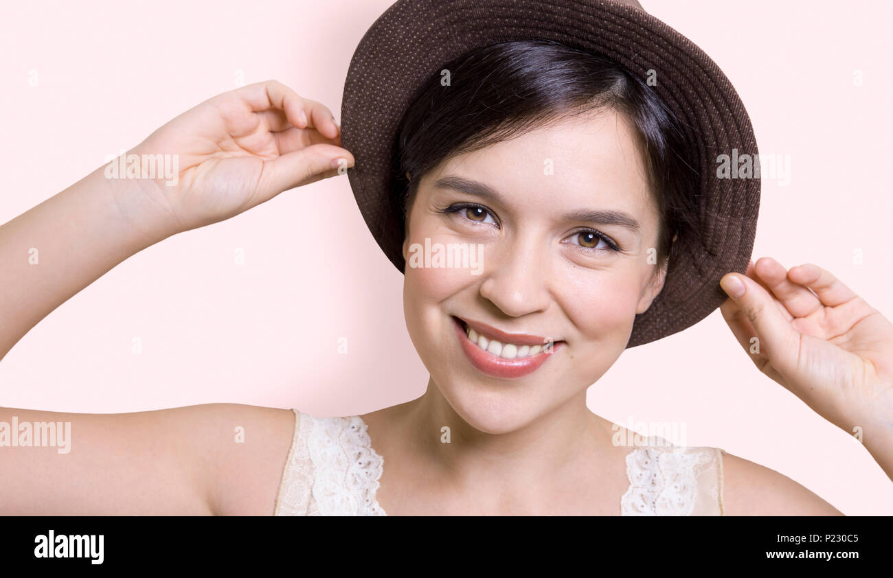 Young attractive woman holding her hat and smiling Banque D'Images