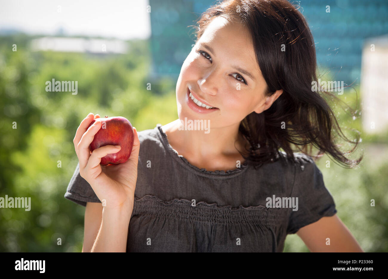 Young attractive woman holding red apple and smiling Banque D'Images