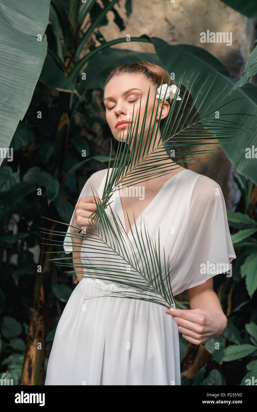 Fille d'offres en robe d'été blanche posant avec des feuilles de palmier  tropical Photo Stock - Alamy