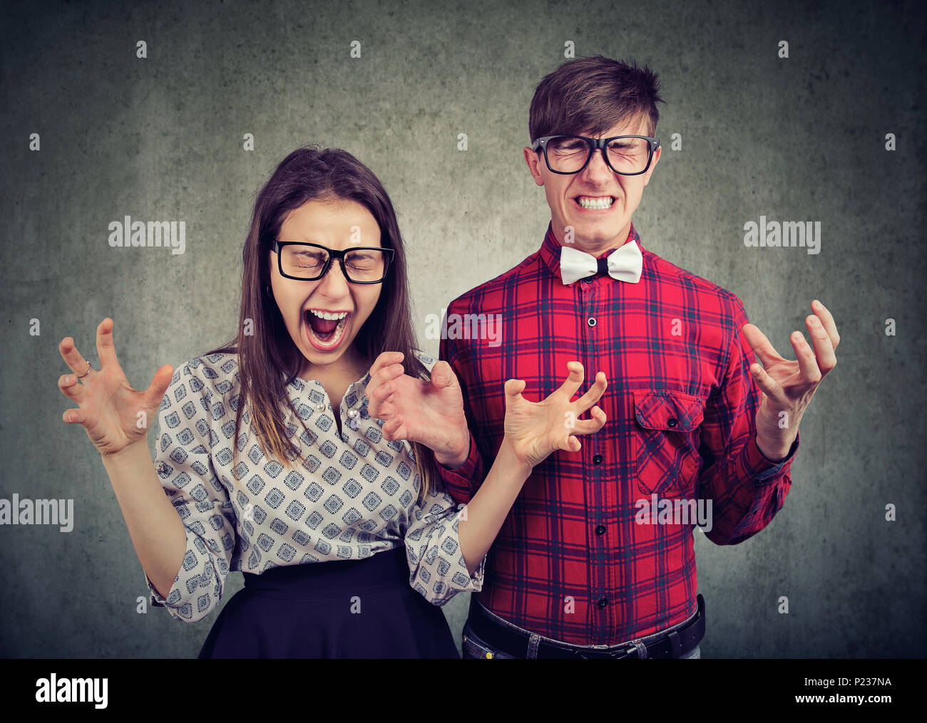 Souligné desperate angry couple hurlant debout près de l'autre sur grunge wall background Banque D'Images