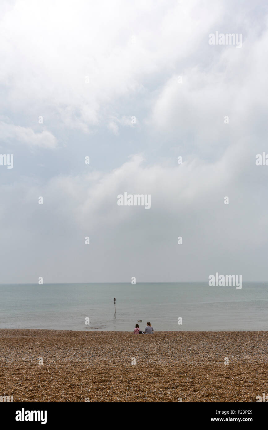 Les filles à la recherche de couple isolé de l'horizon à Hastings Beach, Hastings, East Sussex, Angleterre , Royaume-Uni Banque D'Images