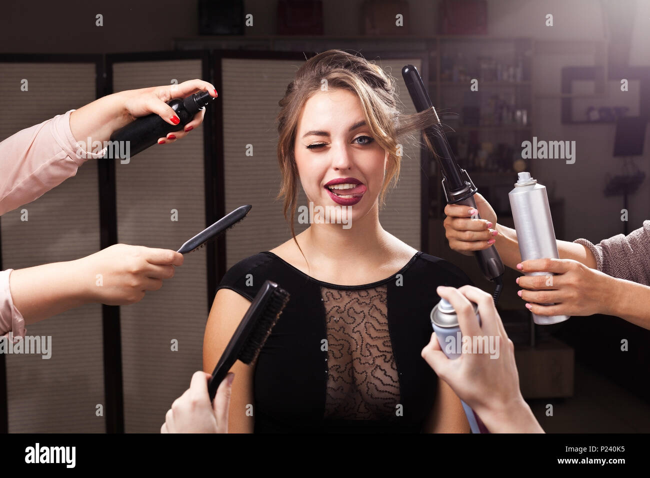 Fille grimaçant entouré par les mains avec les produits de maquillage Banque D'Images