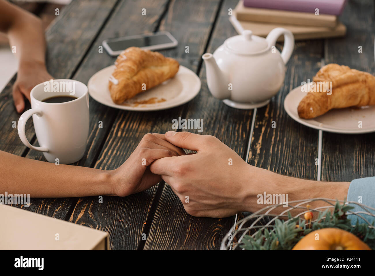 Close-up view of couple holding hands on table avec petit déjeuner Banque D'Images