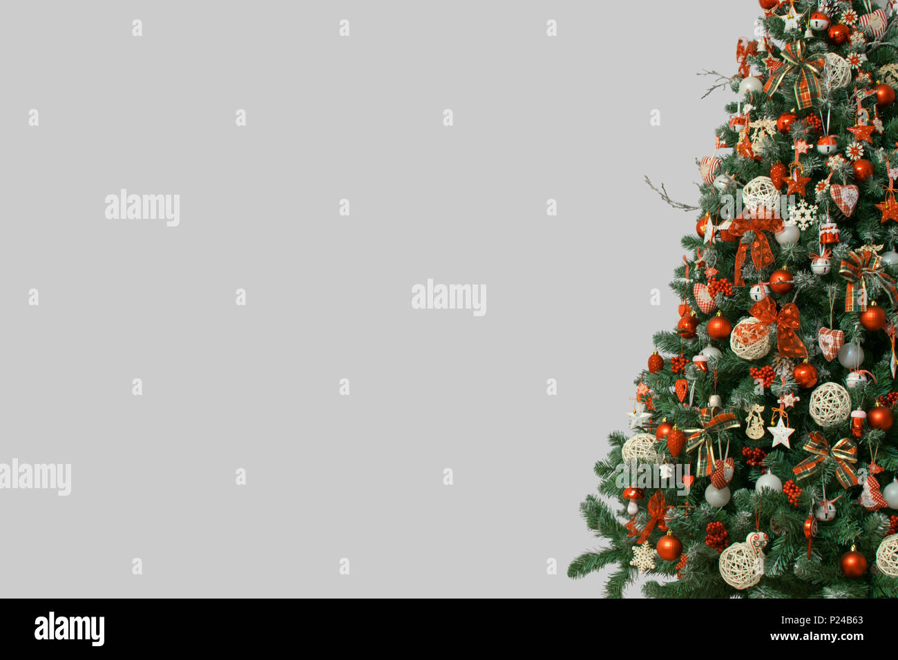 La moitié de l'arbre de Noël isolé sur fond gris, décoré avec des ornements de cru ; ratan, boules et rubans de toile tartan, flocons en bois Banque D'Images