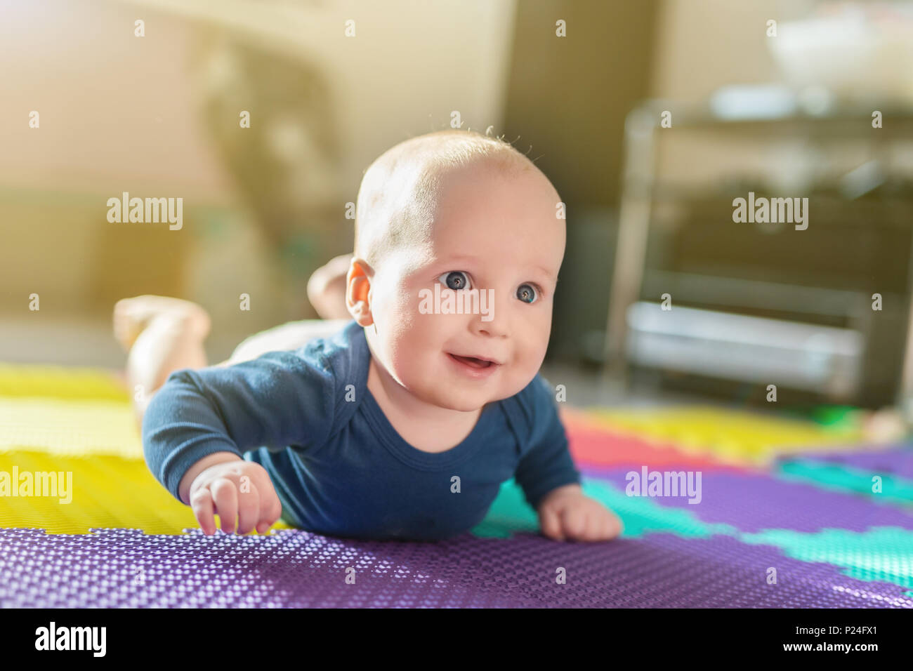Portrait of cute caucasian baby boy crawling sur le doux tapis de jeu à l'intérieur. Adorable enfant s'amusant à faire de premiers pas sur parole à la pépinière. Bac Banque D'Images
