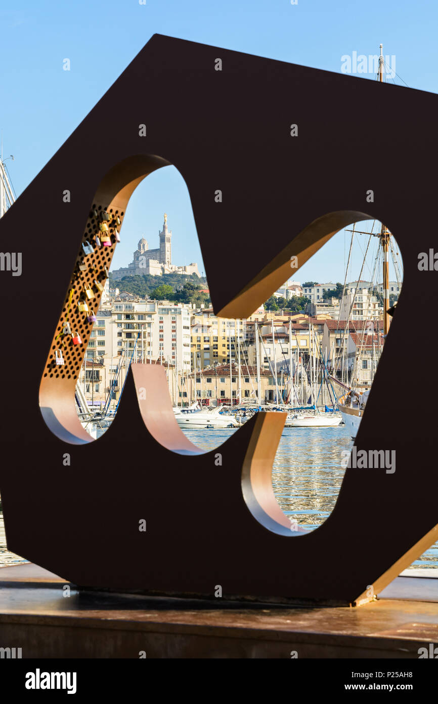 La Basilique de Notre-Dame de la Garde vue depuis le Vieux Port via le logo M de la ville de Marseille, avec l'amour d'isolation et de bateaux dans la marina. Banque D'Images