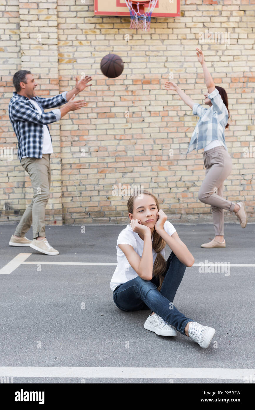 Fille bouleversé avec happy parents jouant au basket-ball derrière Banque D'Images