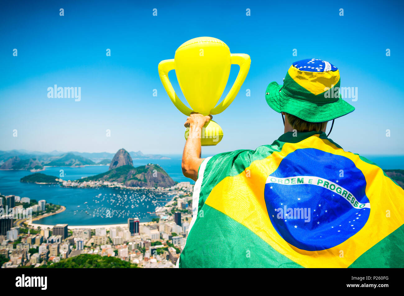 Champion du Brésil enveloppée dans un drapeau holding trophy de Sugarloaf Mountain View Botafogo Rio de Janeiro au Brésil. Banque D'Images