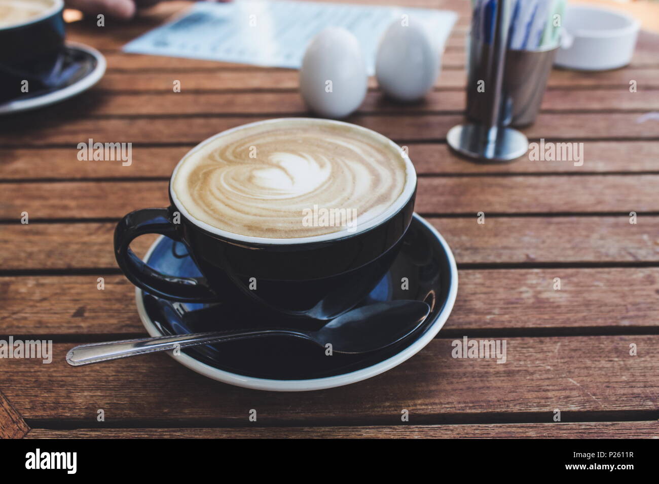 Close up image d'une tasse de café chaud dans une tasse noire Banque D'Images