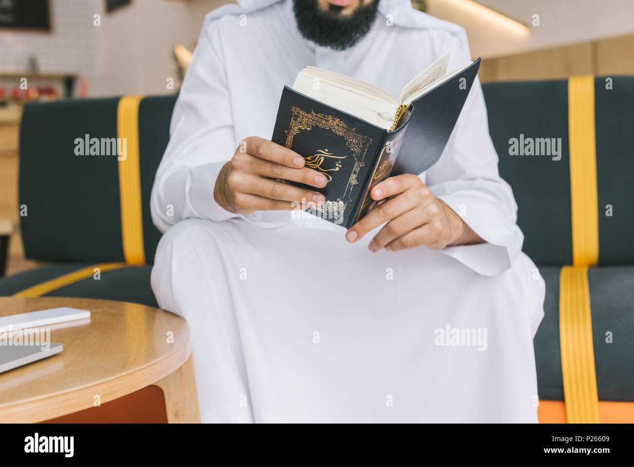 Cropped shot of Muslim man reading quran in cafe Banque D'Images