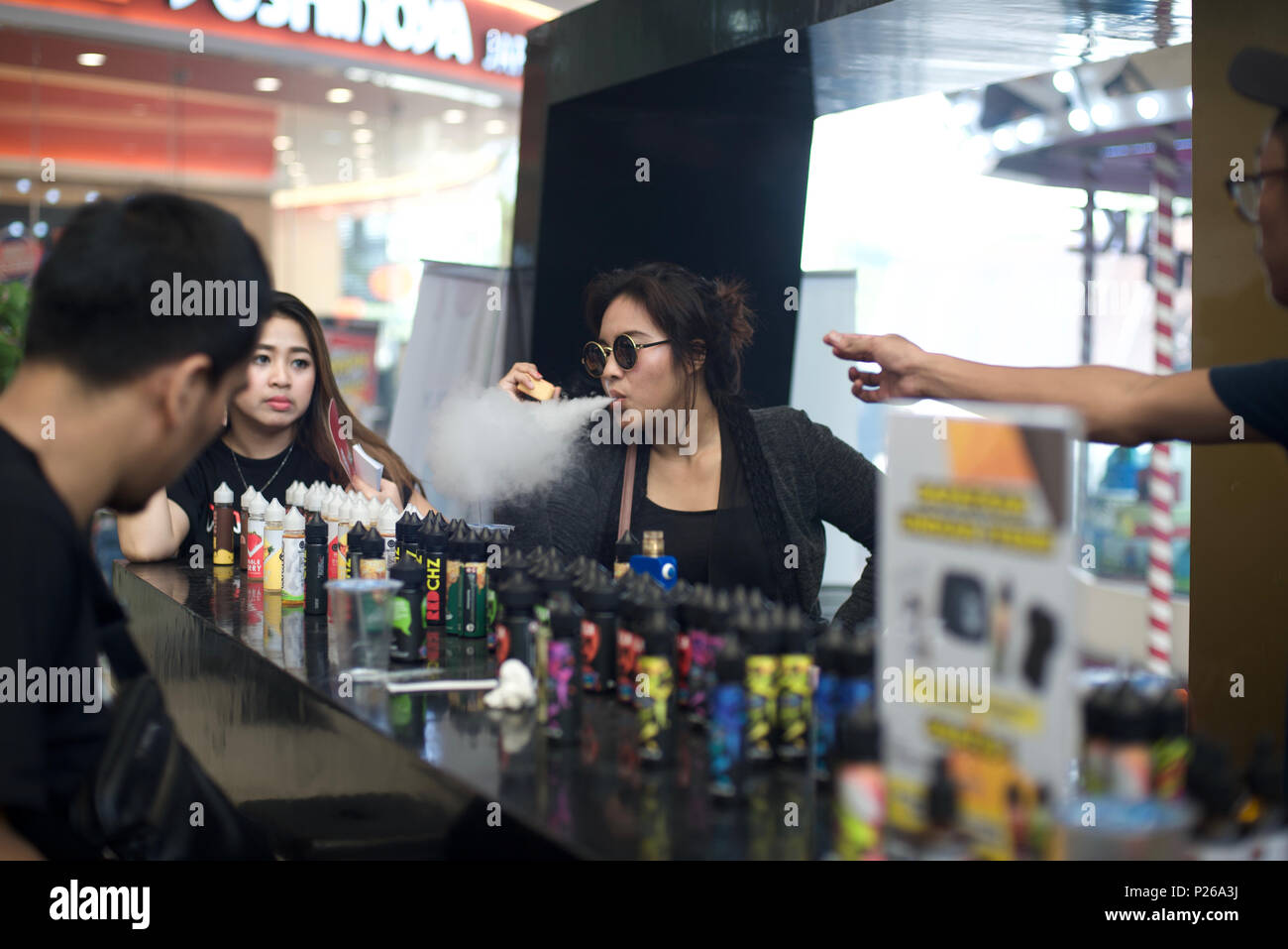 Une femme exhalle la vapeur tout en faisant des achats dans un stand de liquide de e-cigarette lors d'une foire de la vape à Jakarta, en Indonésie. © Reynold Sumayku Banque D'Images