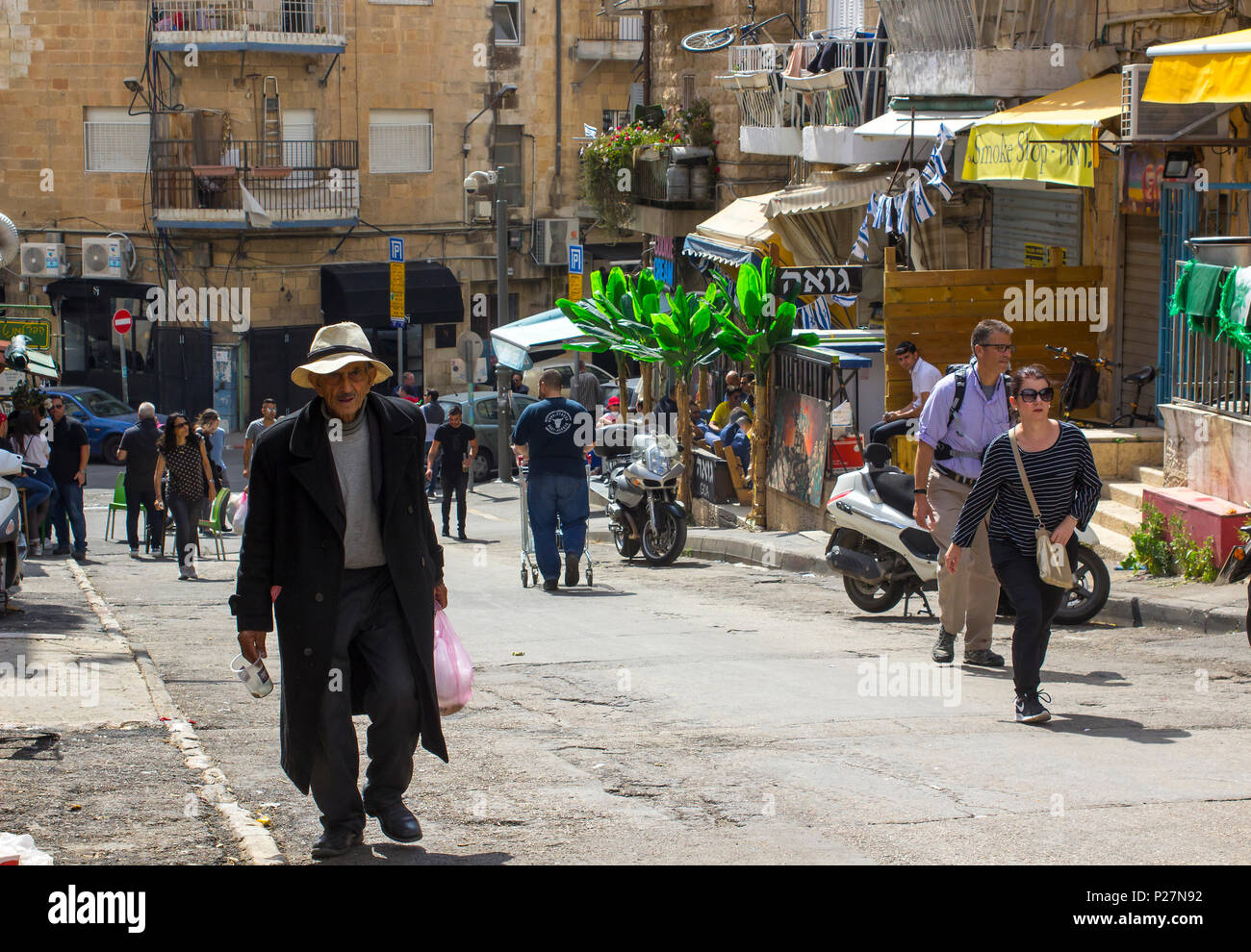 9 mai 2018 Un homme d'âge mûr d'un long manteau sombre et floppy hat faisant son chemin jusqu'à une colline à l'animation de la rue du marché Mahane Yehuda à Jérusalem Israël Banque D'Images
