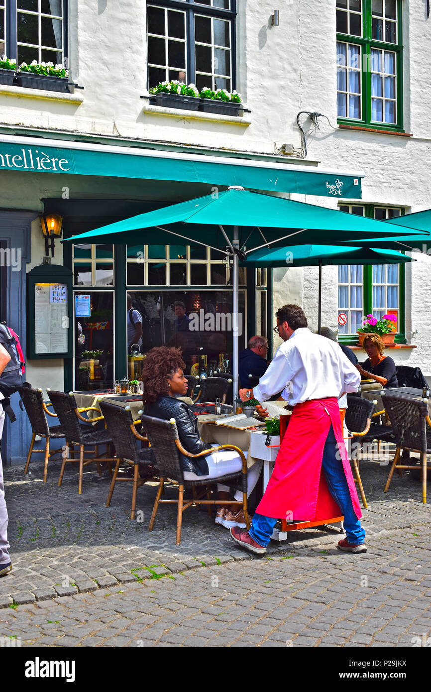 Une jolie femme de couleur à l'chat serveur dans un restaurant du centre-ville popluar à l'heure du déjeuner à Bruges ou Brugge, Belgique Banque D'Images