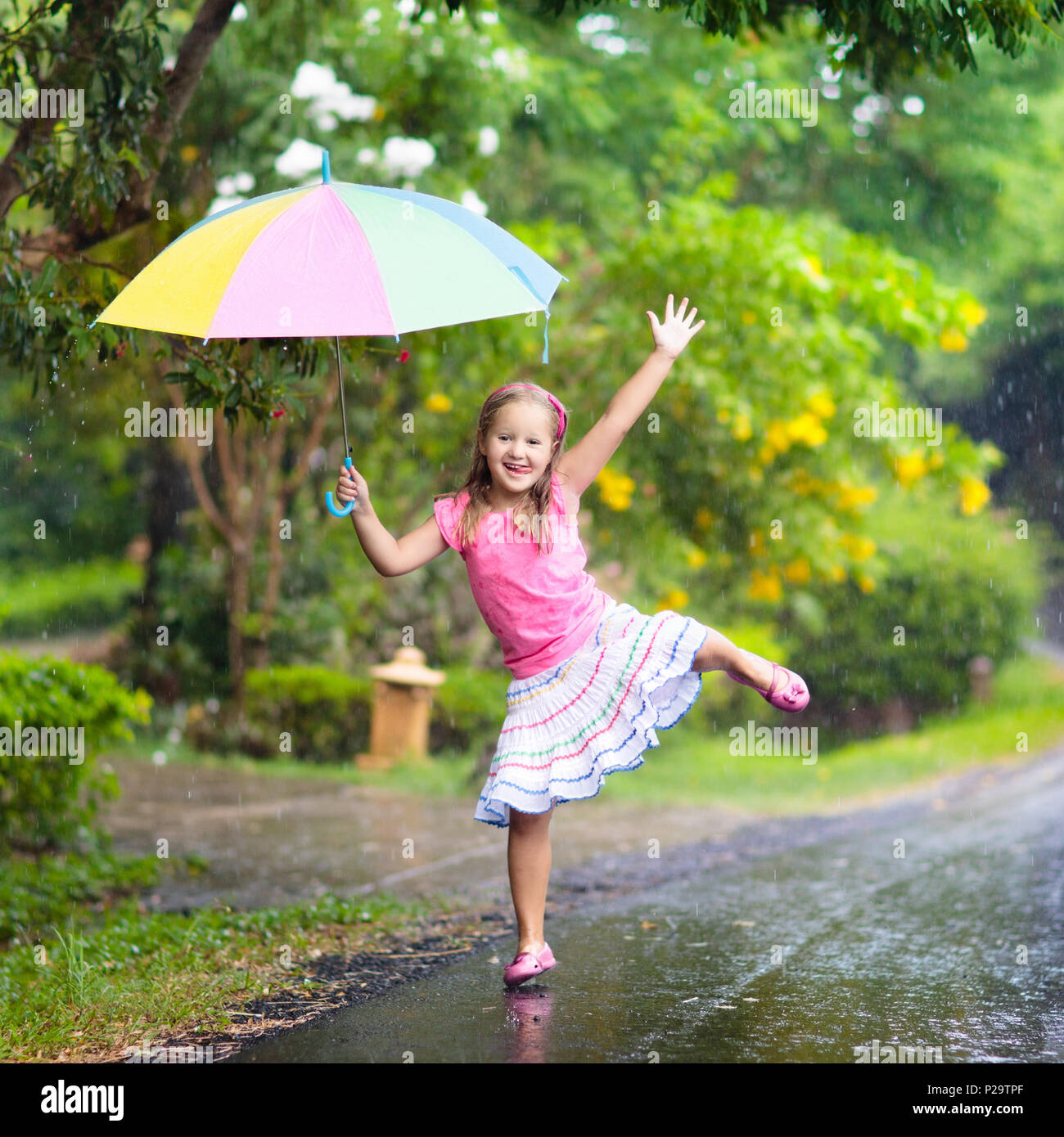 Kid jouer dehors sous la pluie. Les enfants jouent dehors avec parapluie en  cas de pluie. Petite fille pris en premier ressort d'une douche. Kids Fun  en plein air par rainy Photo