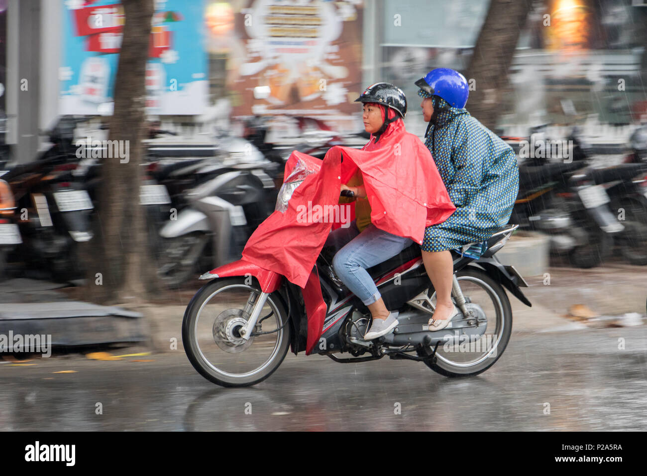 SAIGON, Vietnam, DEC 14, 2017 personnes avec un imperméable ride sur une moto sous la pluie. Le transport dans la ville quand il pleut. Banque D'Images