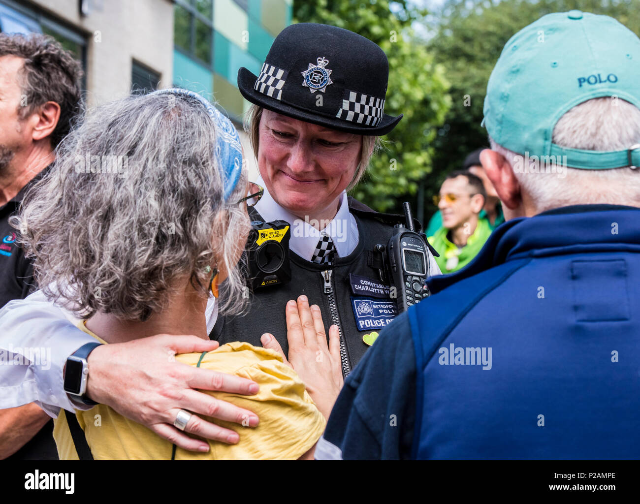 Agent de police féminin hugging woman à la base de la tour de Grenfell, où les membres de la famille et amis des victimes se rassemblent pour marquer le premier anniversaire de l'incendie, Londres, Angleterre, Royaume-Uni, le 14 juin 2018 Banque D'Images