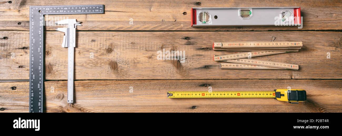 Outils de menuiserie. Ruban de mesure, niveau de l'esprit et des règles sur fond de bois, bannière, copie espace, vue du dessus Banque D'Images