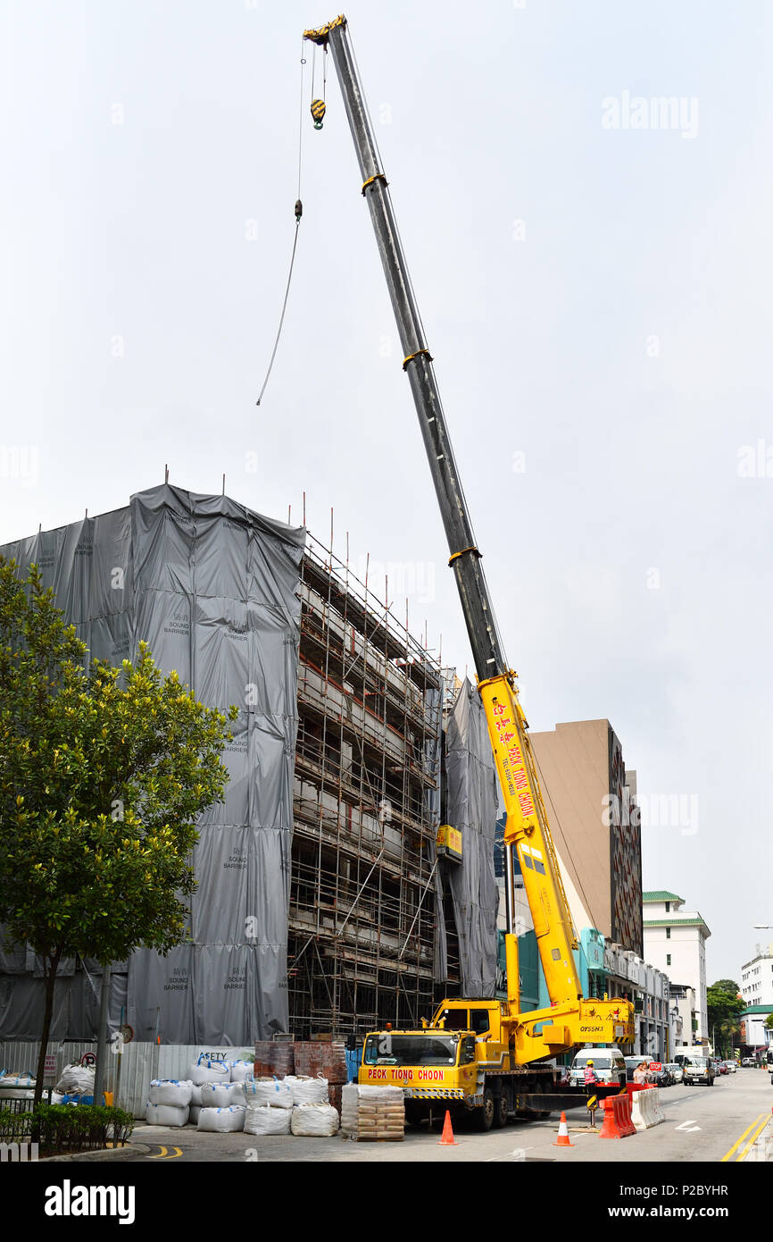 Singapour. Travailleurs étrangers l'exploitation d'une grande grue télescopique utilisé pour la construction. C'est sous la propriété de Peck Thiong Choon. Banque D'Images