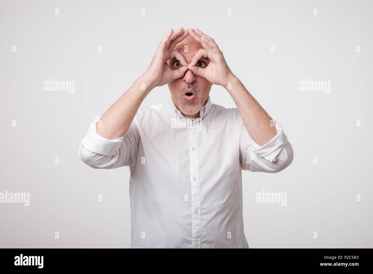 Young caucasian man showing owl signe avec les doigts. Banque D'Images