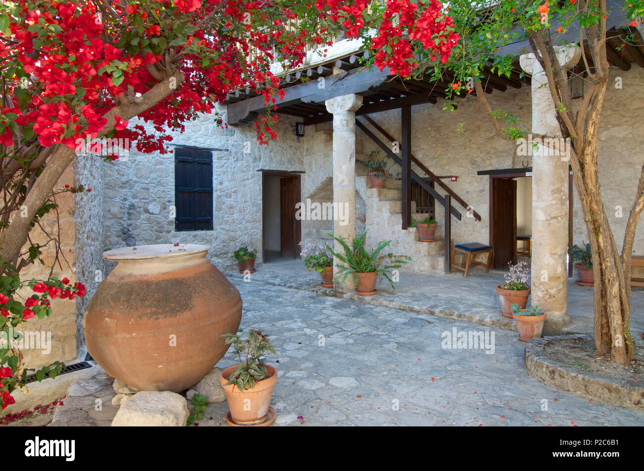 Fleurs de bougainvilliers rouges dans la cour d'un immeuble en pierre au Musée du Folklore à Geroskipou près de Nea Paphos, Paphos, Chypre Banque D'Images