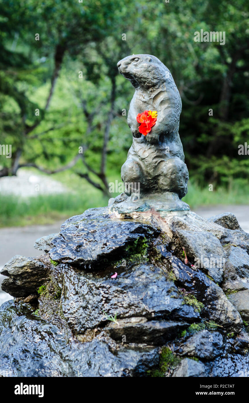 Une marmotte en bronze avec des fleurs fraîches dans ses pattes sur une fontaine, Champex, canton du Valais, Suisse Banque D'Images