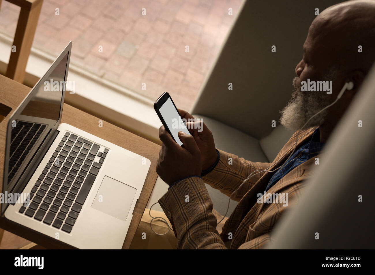 Senior graphic designer using laptop in cafeteria Banque D'Images