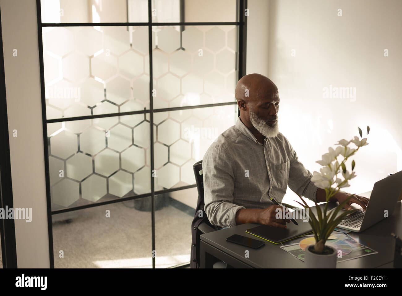 Senior graphic designer à l'aide de tablette graphique et laptop at desk Banque D'Images