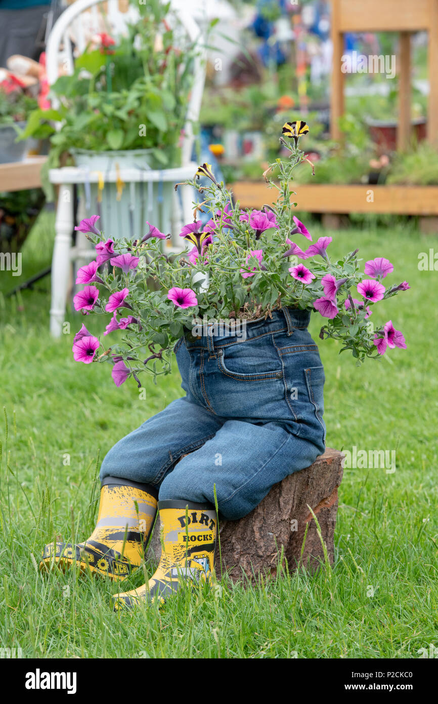 Childs inhabituelle des jeans et des bottes wellington utilisé comme un pot de fleur à un flower show. UK Banque D'Images