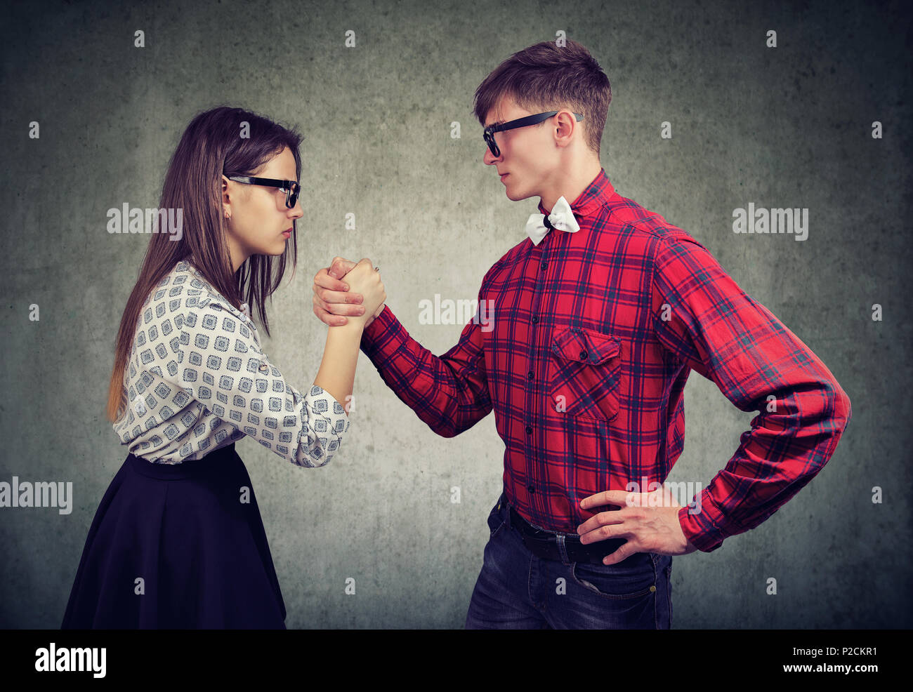 Jeune homme et femme ayant la concurrence dans le bras de fer à l'un l'autre dans la domination. Banque D'Images