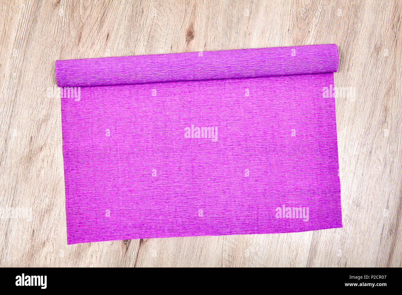 L'un s'est déroulé le rouleau de papier froissé lilas se trouve sur le plancher en chêne. Banque D'Images