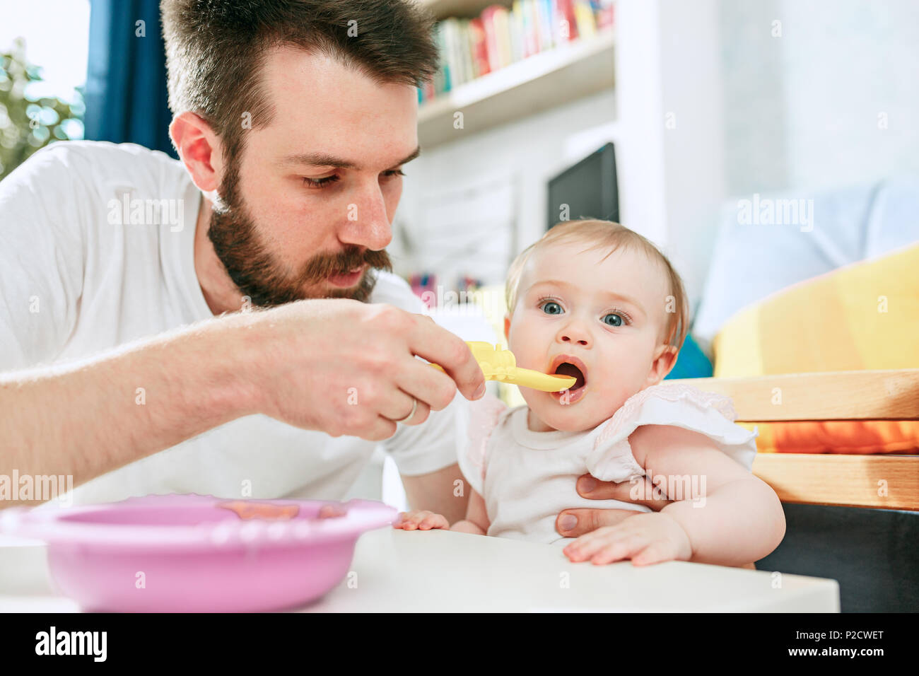 Bon Jeune Homme Qui Mange Son Petit Dejeuner Et Nourrir Son Bebe A La Maison Photo Stock Alamy