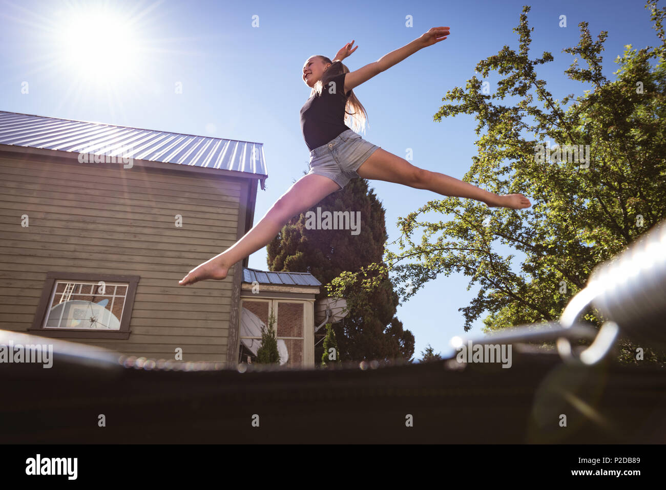 Girl jumping on trampoline de jardin Banque D'Images