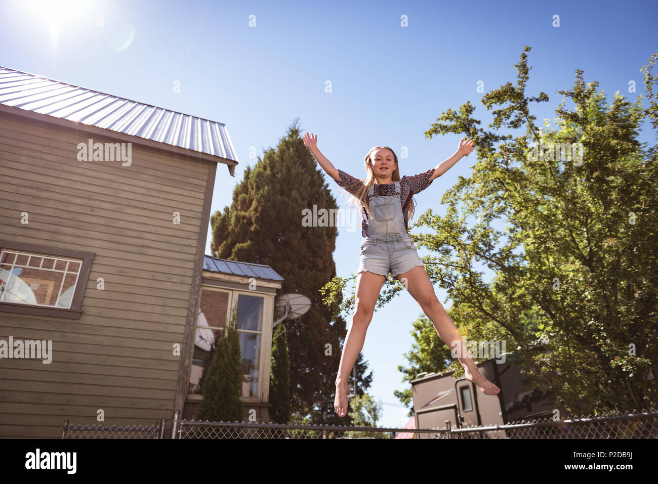 Girl jumping on trampoline de jardin Banque D'Images