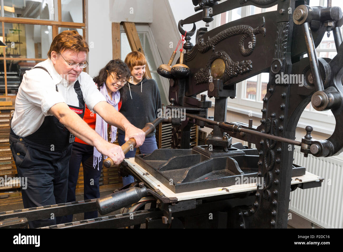 Musée de l'impression Arts Leipzig, travailleur et visiteurs à la machine d'impression, Type Foundry, Leipzig, Saxe, Allemagne Banque D'Images