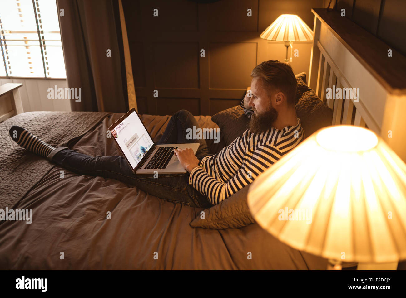 Man lying on bed while using laptop Banque D'Images