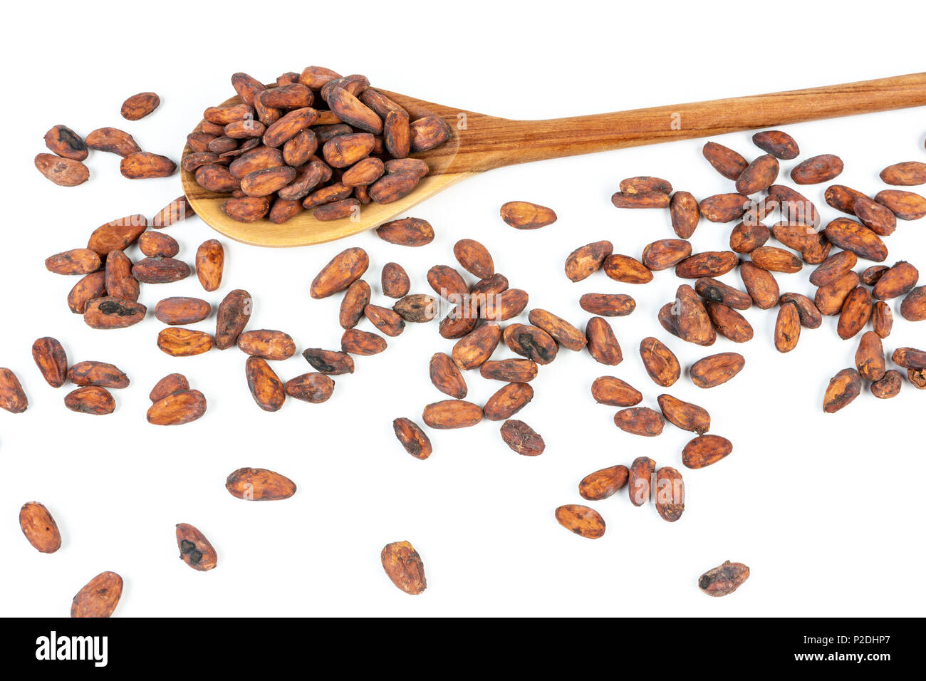 Fèves de cacao dans une cuillère de bois et sur fond blanc. Banque D'Images