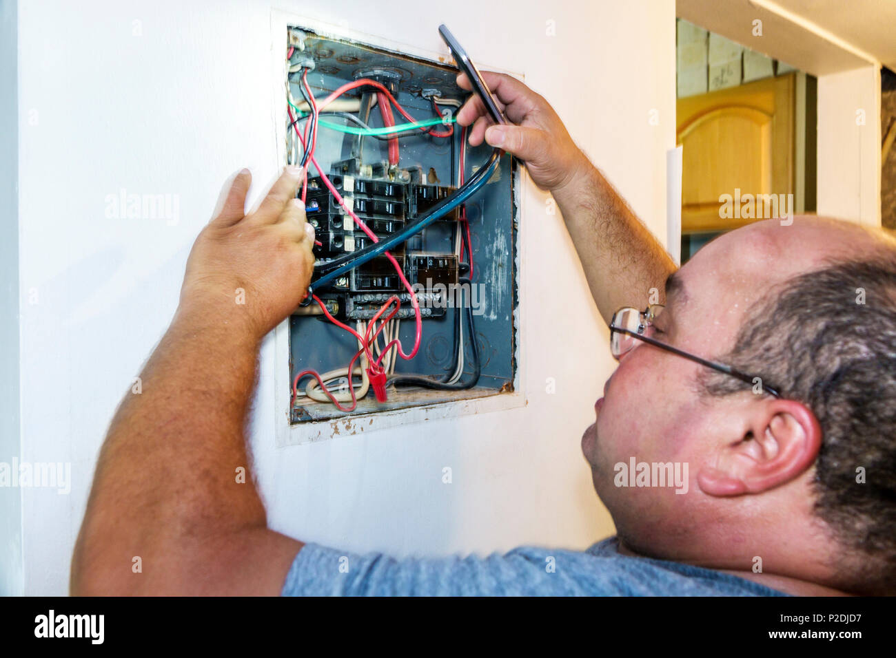 Miami Beach Florida,hispanique,immigrants,homme hommes,électricien,travail,tableau électrique,boîtier de disjoncteurs,fils,travail,réparation,FL17 Banque D'Images
