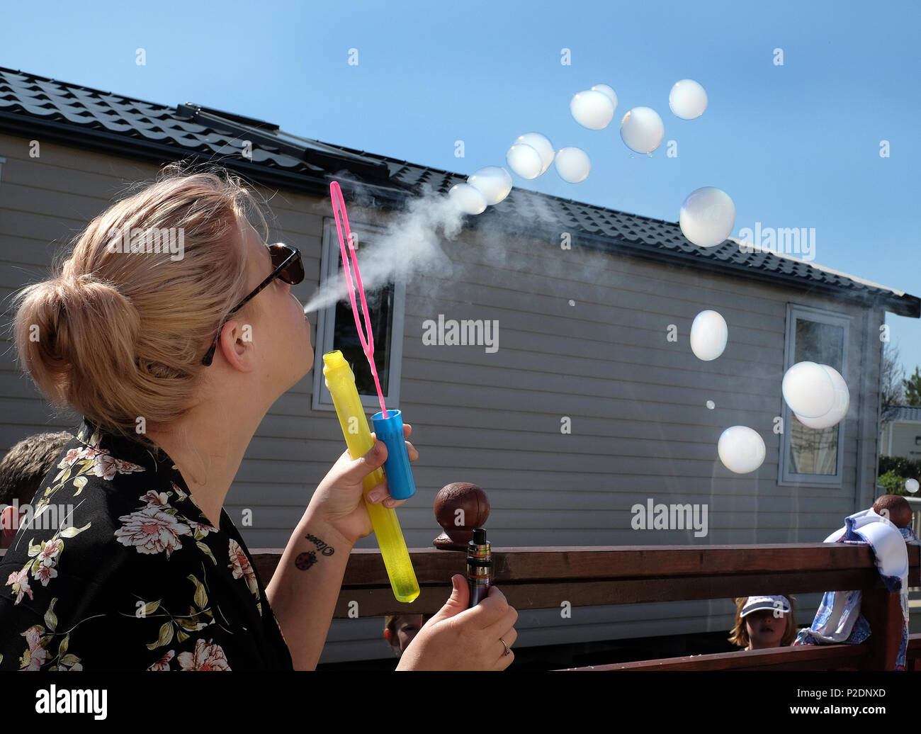 Woman blowing bubbles les remplir de fumée d'une cigarette vaping moderne. Banque D'Images