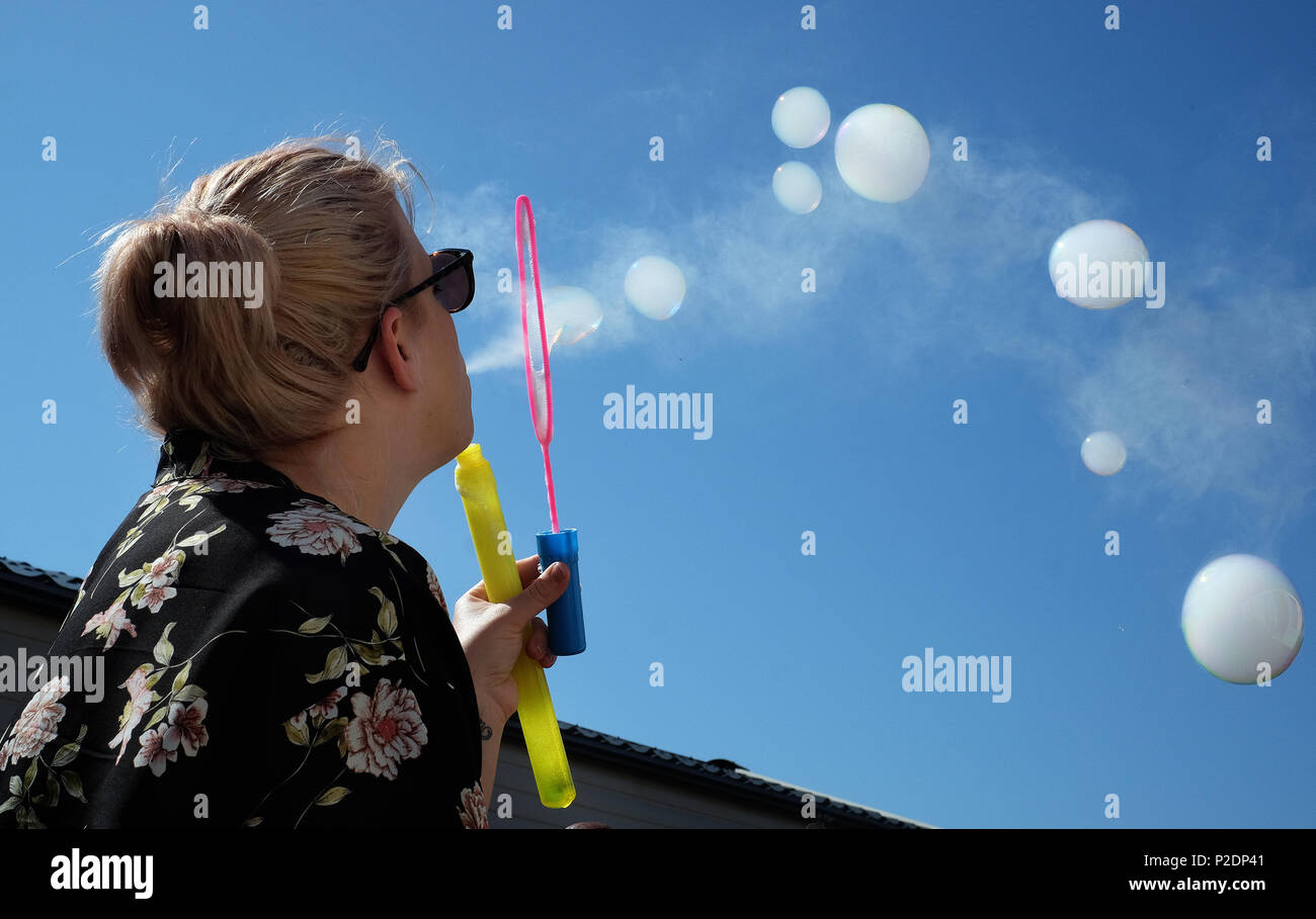 Woman blowing bubbles les remplir de fumée d'une cigarette vaping moderne. Banque D'Images