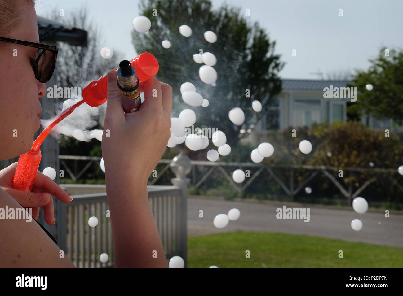 Woman blowing bubbles les remplir de fumée d'une cigarette vaping moderne. Banque D'Images