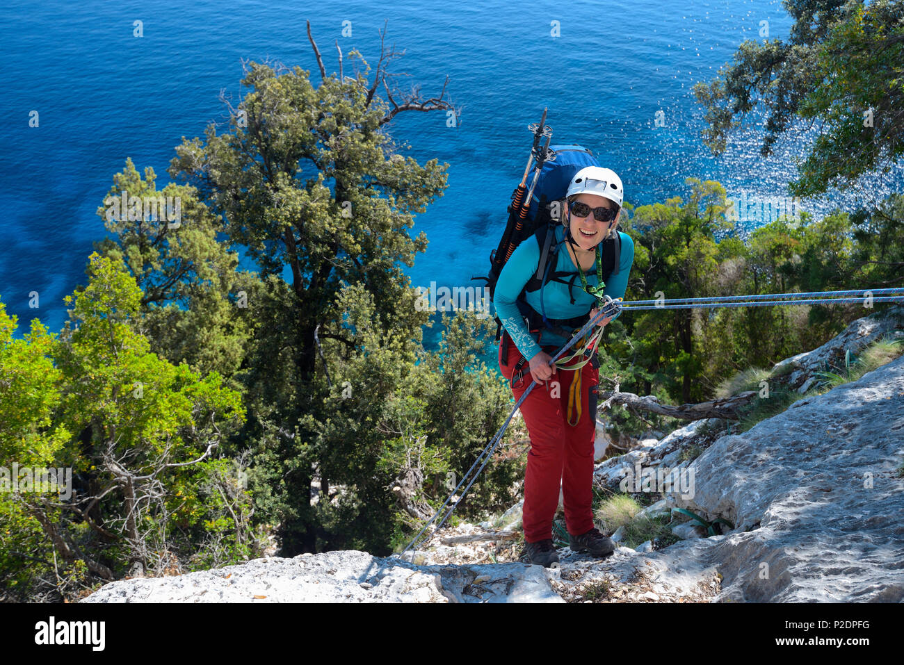 Une jeune femme avec de la descente en rappel dans le trekking paysage littoral montagneux au-dessus de la mer, Golfo di Orosei, Selvaggio blu, S Banque D'Images