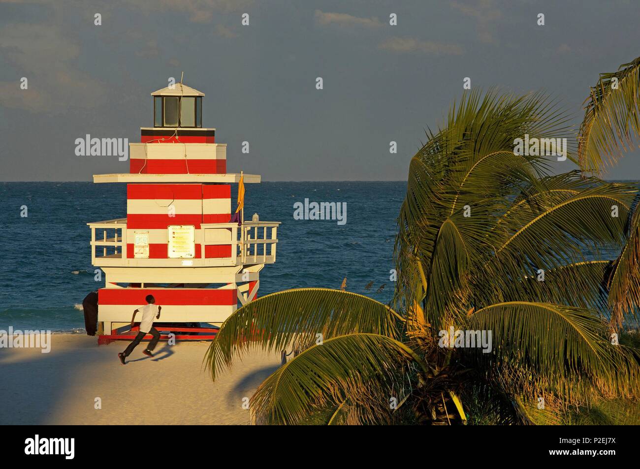 États-unis, Floride, Miami, les jeunes en cours d'exécution sur la plage, à proximité d'un poste de premiers secours rétro, en face du point Sud parc, sur la plage, dans le quartier de South Beach, à Miami Beach Banque D'Images