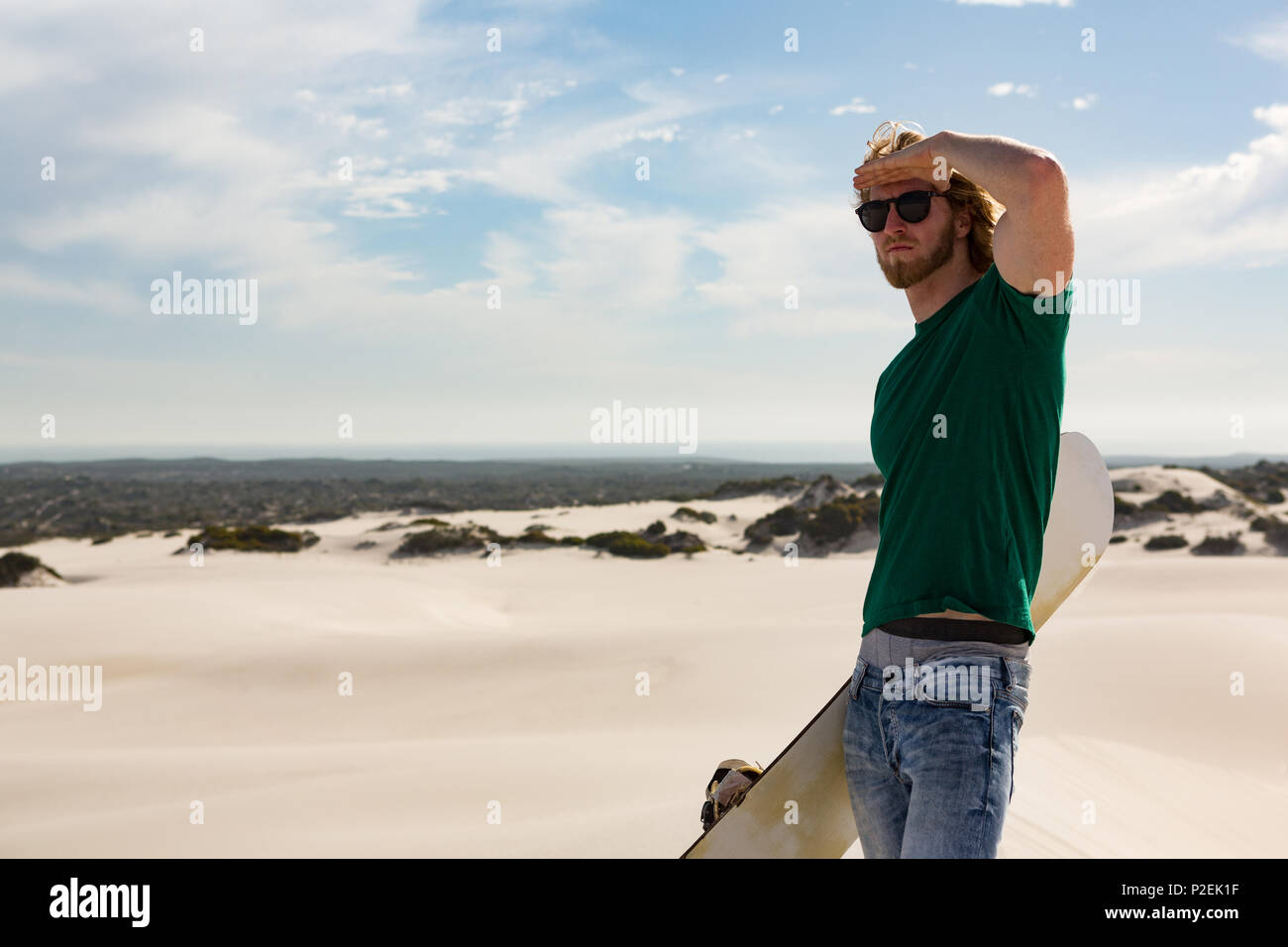 L'homme avec le sandboard debout dans le désert Banque D'Images
