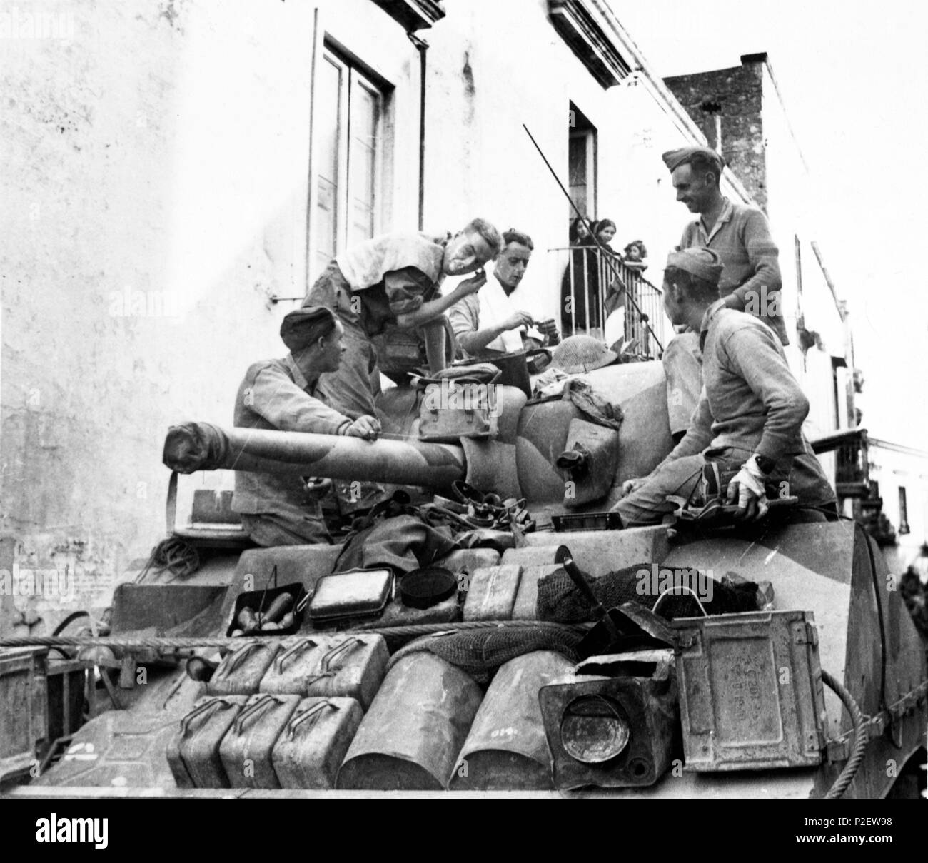 Invasion de l'Italie - 5e armée britannique avance au nord de Naples. Photo montre : les citoyens de la ville de San Martín de sortir sur leur balcon pour regarder un homme de chars britannique ayant un rasage rapide sur le dessus de son réservoir dans la rue. Banque D'Images