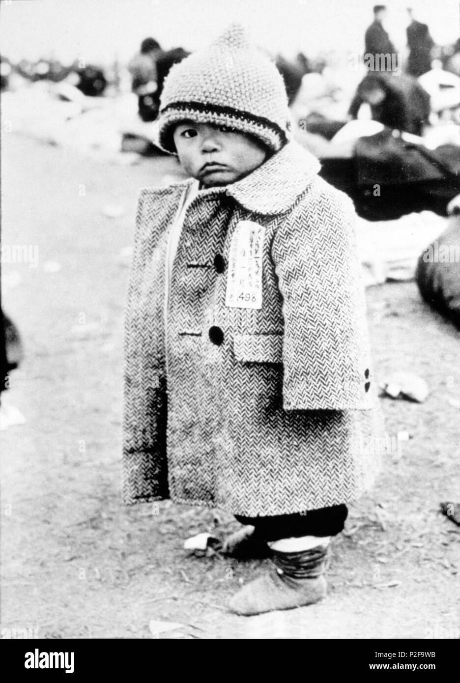 Ce jeune homme, vêtu d'un grand manteau et portant une étiquette de l'empêcher de se perdre. L'un de ses plus de 4 millions de Japonais transportées par l'US Navy de loin les ports de l'Est et les îles du Pacifique. 1945. Banque D'Images
