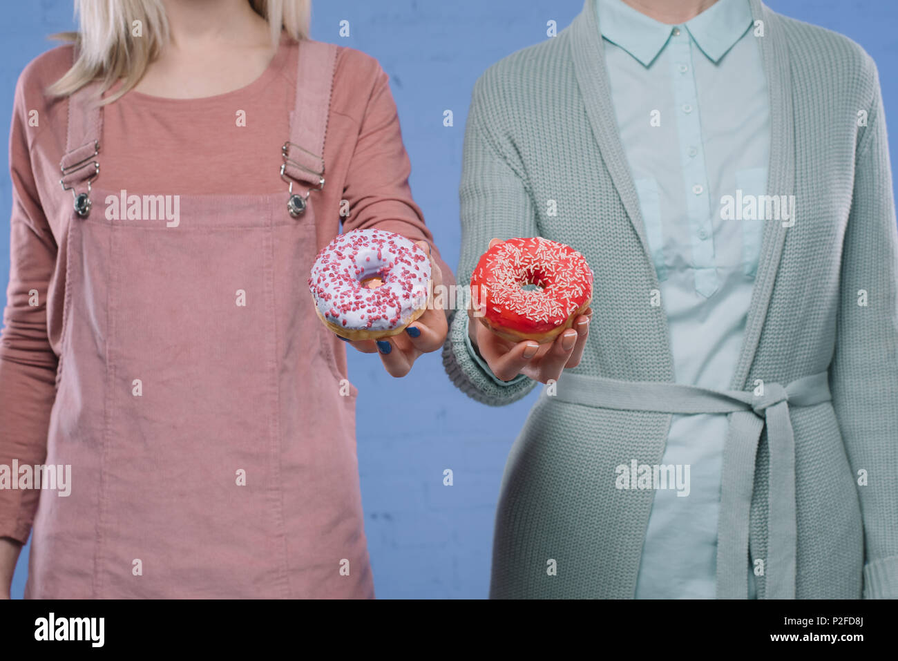 Cropped shot of women holding élégant vitrage donuts Banque D'Images