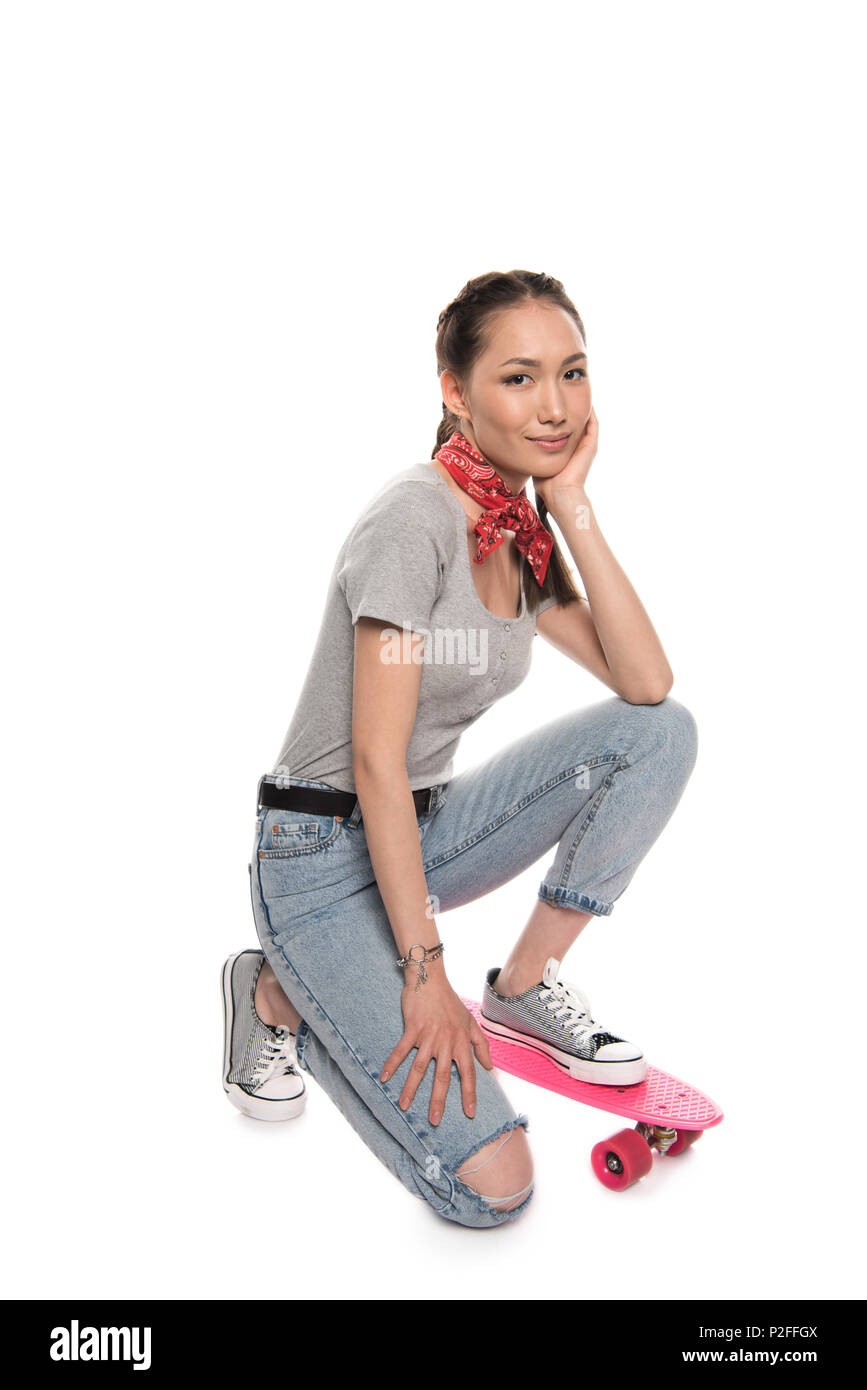 Beautiful asian girl posing with skateboard and looking at camera isolated on white Banque D'Images